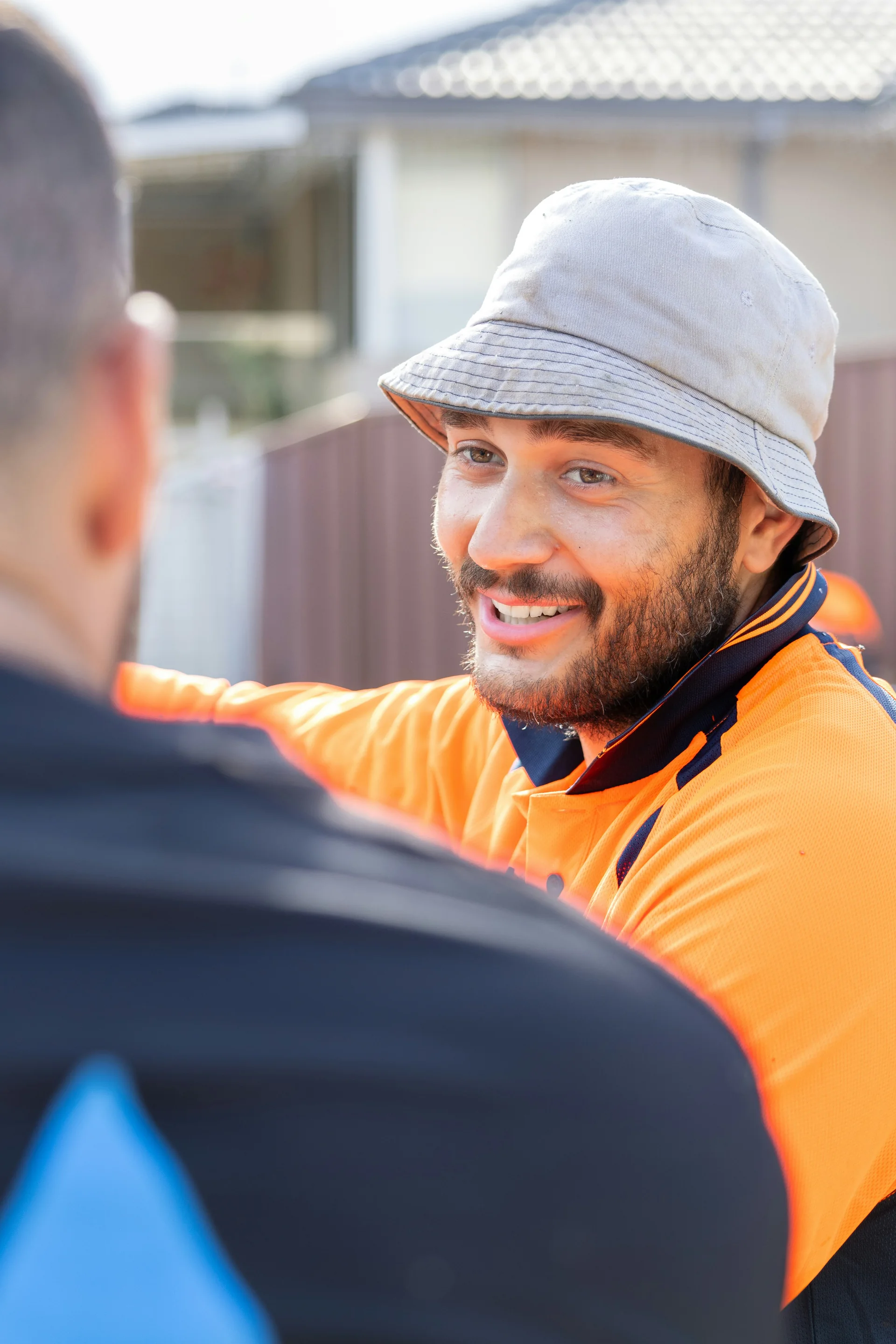 Tradesperson in a high-visibility shirt talking outside a home